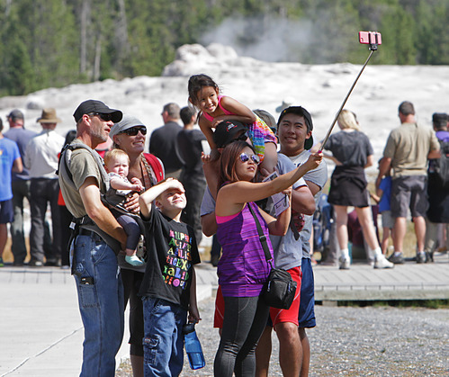 Family taking a selfie at Old Faithful in Yellowstone