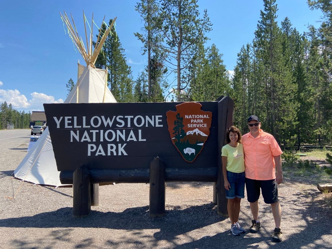 Visitors at the Yellowstone National Park entrance sign